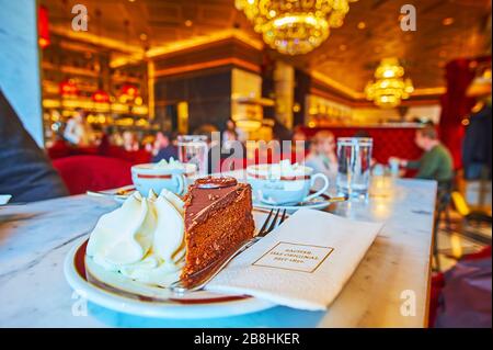 WIEN, ÖSTERREICH - 19. FEBRUAR 2019: Besuchen Sie das traditionelle Café Vienese Sacher und genießen Sie leckeren Schokoladensacher (Sachertorte) mit Schlagsahne, auf Stockfoto