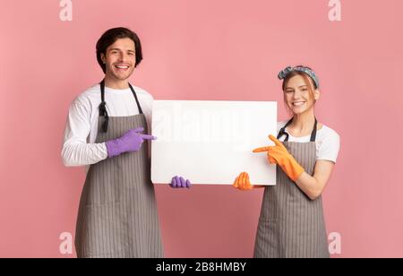 Fröhliches Paar Mit Handschuhen, Das Auf White Placard In Den Händen Zeigt Stockfoto