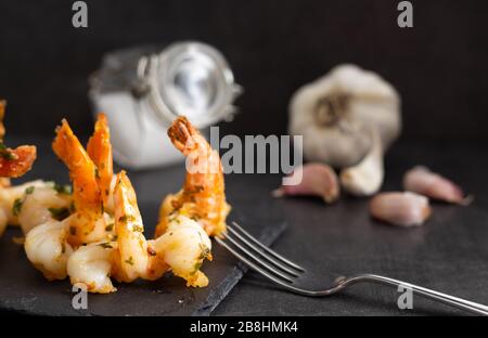 Köstliche Meeresfrüchte. Hausgemachte Garnelen mit Knoblauchsauce auf schwarzem Teller. Stockfoto