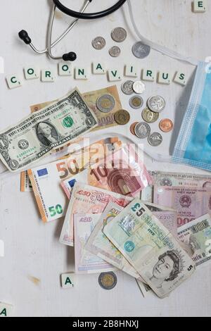 Overhead-Ansicht von Euro, Dollar, Pfund und mehr. In der Oberseite das Wort Coronavirus. Stockfoto