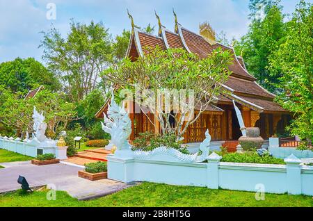Das Gelände des üppigen Laos-Gartens mit Nachbildung des Holztempels Wat Xieng Thong, bewacht von weißen Naga-Schlange, Rajapruek-Park, Chiang Mai, Thailand Stockfoto