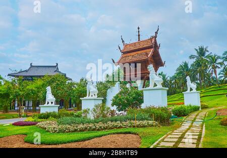 Der malerische Mondop-Pavillon aus Holz, umgeben von statuen von singha-löwen und Blumenbeeten im Rajapruek-Park, Chiang Mai, Thailand Stockfoto