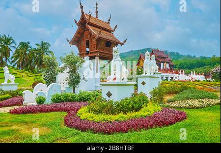 Genießen Sie den malerischen Rajapruek-Park mit Zierblumenbeeten, grünem Rasen, Palmen und kleinem buddhistischen Schrein, der sich im Holzmondop-Pavillon befindet. Stockfoto