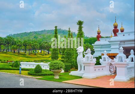 Die malerischen Thuja-Bäume und Pflanzen in Töpfen an der weißen Statue von Singha-Löwen und Gartenvasen, Rajapruek-Park, Chiang Mai, Thailand Stockfoto