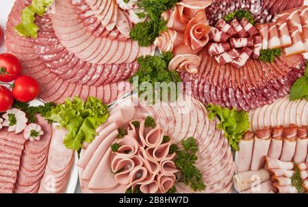 Wurst und gehärtetes Fleisch mit Petersilie auf den weißen Platten schneiden. Draufsicht Stockfoto