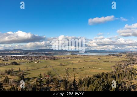 Panoramasicht auf die Landschaft mit Forggensee und Bannwaldsee von Schloss Neuschwanstein an einem sonnigen Wintertag mit blauer Himmelswolke in Backgroun Stockfoto