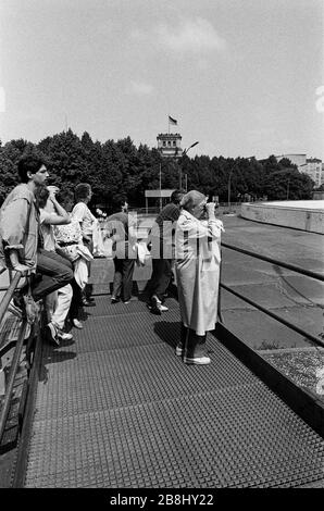 Menschen auf einer Aussichtsplattform, die von der westlichen Seite der Kluft aus auf einen Abschnitt der Berliner Mauer am Brandenburger Tor blickt. Die Berliner Mauer war eine von der Deutschen Demokratischen Republik (DDR, Ostdeutschland) am 13. August 1961 errichtete Barriere, die West-Berlin von der umliegenden DDR und von Ost-Berlin völlig abgrenzte. Die Mauer wurde am 9. November 1989 die freie Personenbewegung von Ost nach West erlaubt. Stockfoto