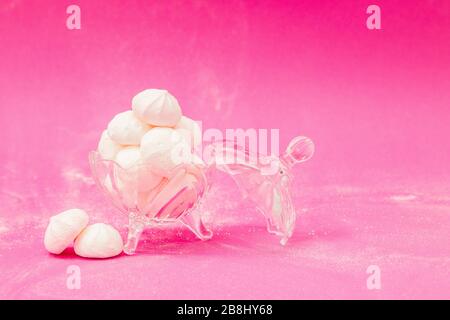 Meringues in einer Glasschale auf pinkfarbenem Hintergrund Stockfoto