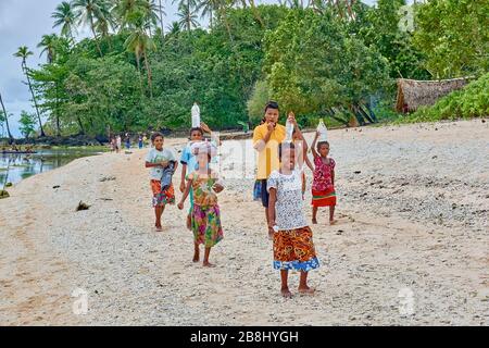Frau, die an der Strandpromenade spazieren geht und die Last auf ihren Köpfen trägt Eingeborenes Eingeborenes Dorf Weibliche Frau Frauen junger Teenager Stockfoto