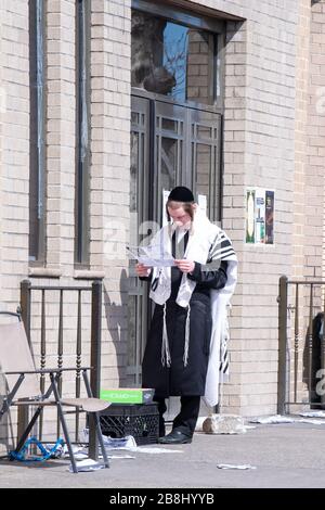 New York, Vereinigte Staaten. März 2020. Ein hasidischer Satmarjude liest einen neuen Brief vor einer Synagoge, der wegen der Verbreitung von Coronavirus in den Vereinigten Staaten für den Dienst am Sabbat geschlossen wurde.die Weltgesundheitsorganisation erklärte Coronavirus (COVID-19) am 11. März zu einer globalen Pandemie. Credit: SOPA Images Limited/Alamy Live News Stockfoto