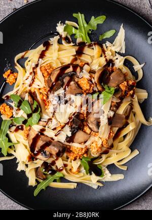 Bolognese Pasta mit Champignons und Arugula zubereitete Balsamiksoße. Draufsicht. Makro. Stockfoto
