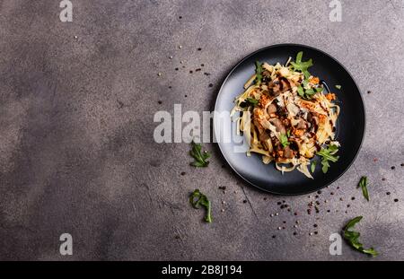 Bolognese Pasta mit Pilzen und Arugula goss Balsamiksoße auf grauem Grund. Platz für Text kopieren. Stockfoto