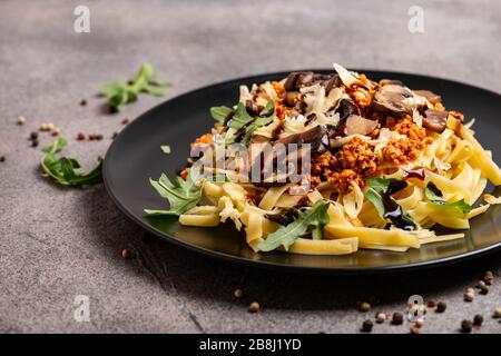 Bolognese Pasta mit Champignons und Arugula zubereitete Balsamiksoße. Nahaufnahme. Stockfoto
