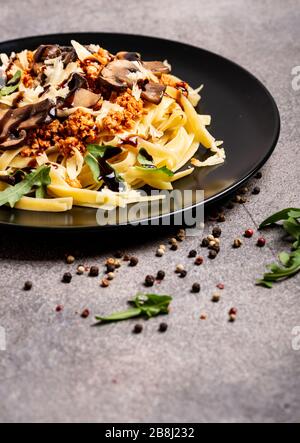Bolognese Pasta mit Champignons und Arugula zubereitete Balsamiksoße. Nahaufnahme. Platz für Text kopieren. Stockfoto