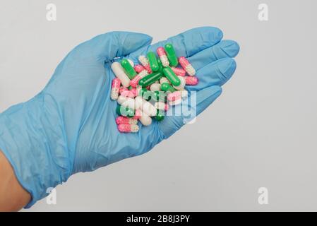 Eine Reihe von Medikamenten Pillen Kapseln in den Händen von Ein menschlicher Arzt in blauen medizinischen Handschuhen Stockfoto