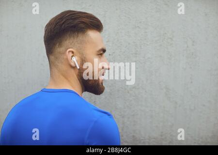 Bärtiger Kerl in Sportkleidung auf grauem Hintergrund. Stockfoto