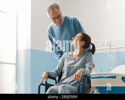 Vater, der ihre Tochter im Rollstuhl im Krankenhaus, in der Familie und im Gesundheitskonzept unterstützt Stockfoto