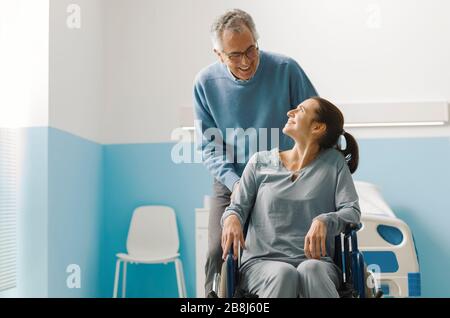 Vater, der ihre Tochter im Rollstuhl im Krankenhaus, in der Familie und im Gesundheitskonzept unterstützt Stockfoto