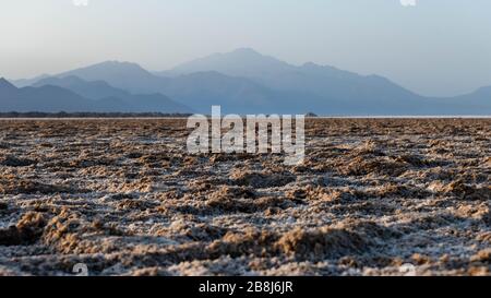 Afrika, Dschibuti, Assalsee. Salzstruktur auf dem Boden mit Bergen im Hintergrund Stockfoto