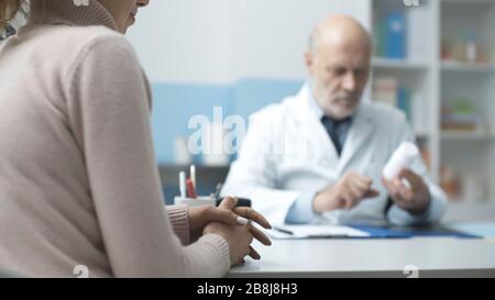 Professioneller Oberarzt, der einen Patienten im Büro betagt und ein verschreibungspflichtiges Medikament gibt Stockfoto