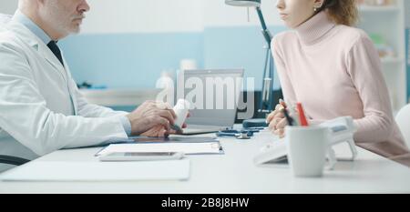 Professioneller Oberarzt, der einen Patienten im Büro betagt und ein verschreibungspflichtiges Medikament gibt Stockfoto