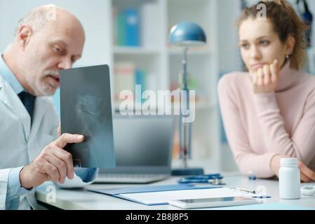 Professioneller Radiologe, der am Schreibtisch sitzt und das Röntgenbild, die Diagnose und das Gesundheitskonzept eines Patienten überprüft Stockfoto