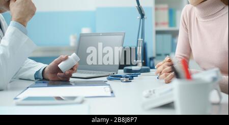 Professioneller Oberarzt, der einen Patienten im Büro betagt und ein verschreibungspflichtiges Medikament gibt Stockfoto