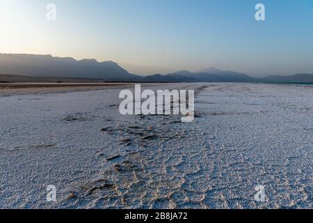 Afrika, Dschibuti, Assalsee. Salzstruktur auf dem Boden mit Bergen im Hintergrund Stockfoto