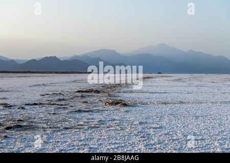 Afrika, Dschibuti, Assalsee. Salzstruktur auf dem Boden mit Bergen im Hintergrund Stockfoto