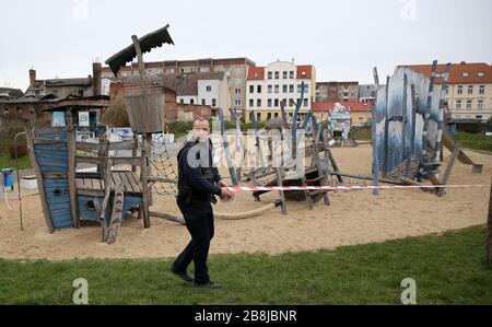 Magdeburg, Deutschland. März 2020. Nils Schufft, Gruppenleiter der Stadtwache, schließt den Spielplatz "Polarstation" im Norden von Magdeburg mit einem Flatterband ab. Wegen der Einschließungsreihenfolge wegen der Ausbreitung des Coronavirus bleiben Spielplätze geschlossen. Credit: Ronny Hartmann / dpa / Alamy Live News Stockfoto