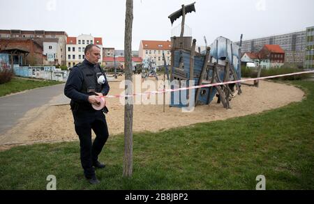 Magdeburg, Deutschland. März 2020. Nils Schufft, Gruppenleiter der Stadtwache, schließt den Spielplatz "Polarstation" im Norden von Magdeburg mit einem Flatterband ab. Wegen der Einschließungsreihenfolge wegen der Ausbreitung des Coronavirus bleiben Spielplätze geschlossen. Credit: Ronny Hartmann / dpa / Alamy Live News Stockfoto