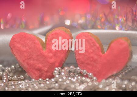 Herzförmige Plätzchen für den Valentinstag auf abstraktem unscharfen Bokeh-Hintergrund. Valentine Herzkekse in Pastellfarben Stockfoto