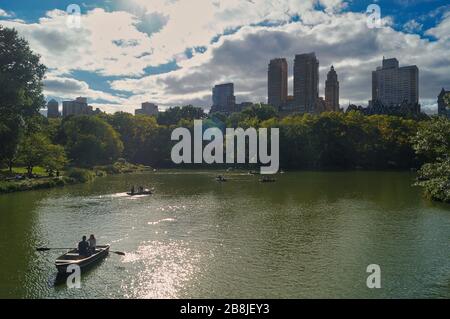 Ein ermüdlicher Tag im Central Park von New Yorks, die Menschen fahren vor Wolkenkratzern im Hintergrund mit Bootstouren. Stockfoto