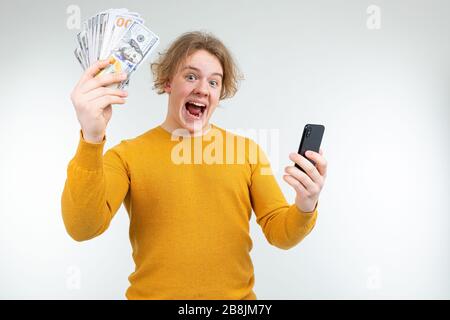 Glücklicher blonder Kerl hält sein Gehalt auf weißem Hintergrund Stockfoto