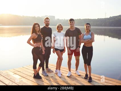 Eine Gruppe von Athleten steht auf dem Hintergrund eines Sees in einem Stadtpark. Stockfoto