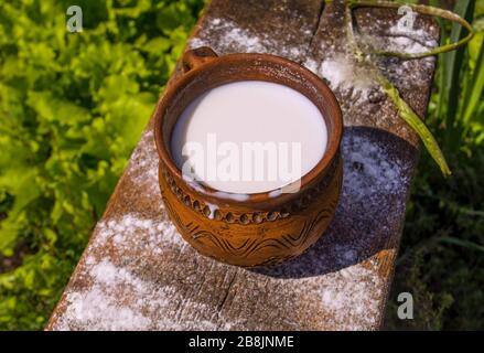 Milch im Becher auf Holztisch. Milch in Vintage-Tasse auf altem Holztisch Stockfoto
