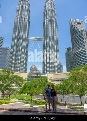 Touristenpaar im KLCC Park vor den Petronas Twin Towers und Suria KLCC Shopping Mall Kuala Lumpur Malaysia. Stockfoto