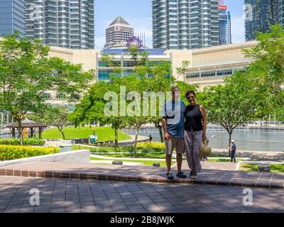 Touristenpaar im KLCC Park vor den Petronas Twin Towers und Suria KLCC Shopping Mall Kuala Lumpur Malaysia. Stockfoto