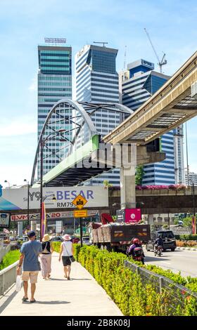 Touristen, die auf dem Fußweg entlang Jalan Sultan Ismail, der KL Monorail-Linie und Bürotürmen in Kuala Lumpur Malaysia spazieren. Stockfoto