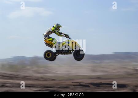 Ein Mann auf einem vierrädrigen atv, der durch die Luft fliegt Stockfoto