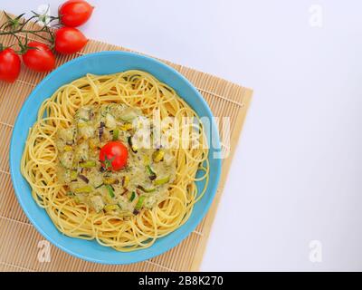 Spaghetti mit einer cremefarbenen Sauce mit Zucchini und Lauch in hellblauer Platte auf weißem Grund von oben. Stockfoto