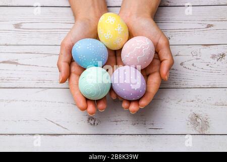 Schöne Frau hält handgemalte ostereier in zarten Pastellfarben über Holztisch. osterkonzept. Stockfoto
