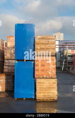 Mehrere Paletten mit Beton Ziegel übereinander im Depot gestapelt. Die industrielle Produktion von Backsteinen. vertikale Foto. Stockfoto