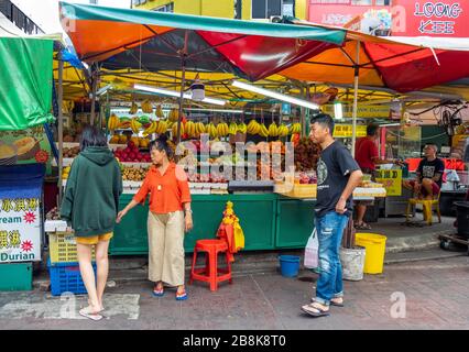 Vender und Kunde am Marktstand für frisches Obst in der Jalan Alor Street Bukit Bintang, Kuala Lumpur Malaysia. Stockfoto