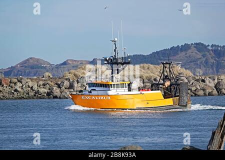 Ein großes, farbenfroher kommerzielles Fischerboot segelt auf dem Weg zum Pazifischen Ozean durch den Steg von Newport, Oregon. Stockfoto