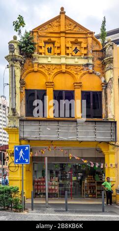 Mann steht vor einem traditionellen Ladenhaus mit chinesischen Buchstaben an der Fassade in Chinatown Kuala Lumpur Malaysia. Stockfoto