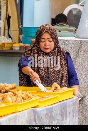 Frau trägt Tudong, die Gebäck in einem Stand in Kasturi Walk Märkte neben Central Market Kuala Lumpur Malaysia vorbereitet. Stockfoto