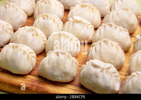 Rohe Manty-Knödel, beliebte asiatische Mahlzeit auf Holzbrett, Nahaufnahme Stockfoto