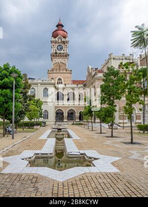 Zentraler Uhrturm mit kupferfarbener Zwiebelkuppel und Teich in Form des islamischen Symbolsterns Rub el Hizb im Sultan Abdul Samad Building Kuala Lumpur Malaysia. Stockfoto