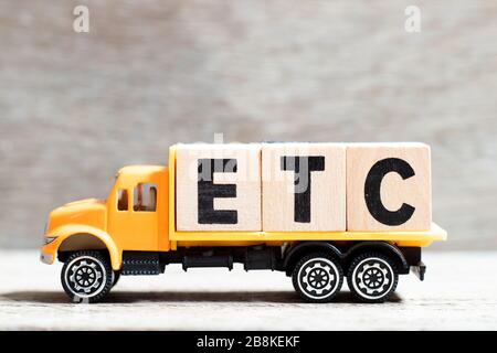 Fahrzeug hält Buchstabenblock in Wort usw. (Abkürzung von et cetera) auf Holzhintergrund Stockfoto